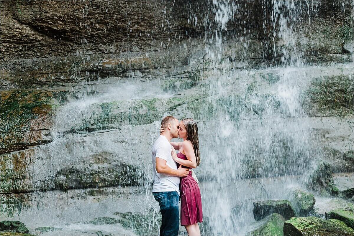 Romantic and timeless photo of engaged couple kissing in front of the waterfall - Rock Glenn falls engagement photographer Dylan Martin Photography in London Ontario
