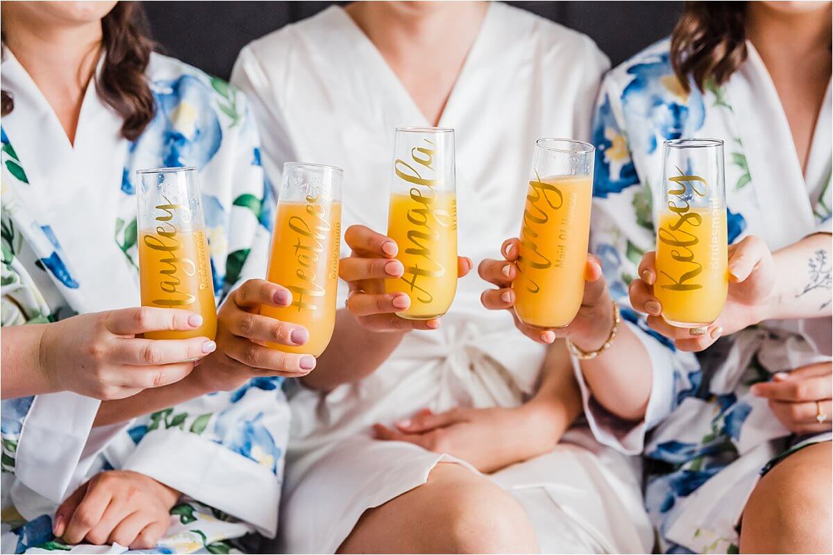 Bride and her bridesmaids hold glasses with their names on it together