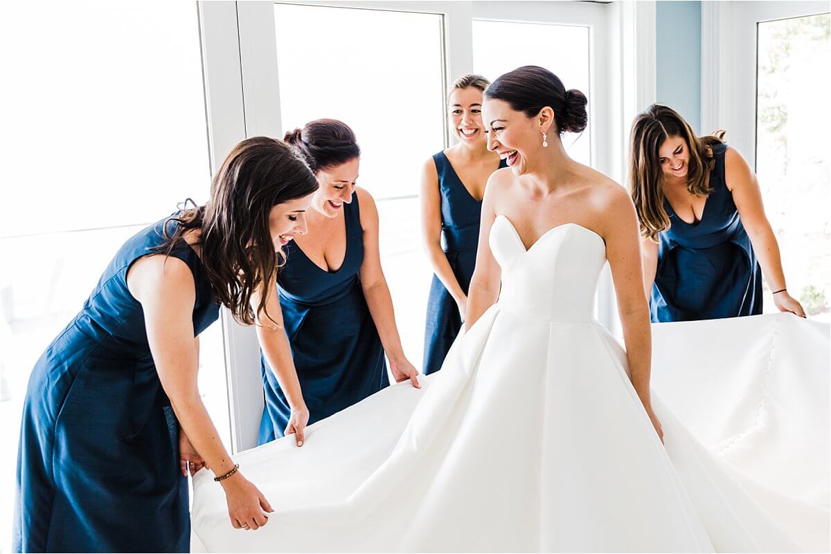 Bride having her cinderella moment with her bridesmaids as they all fix her dress