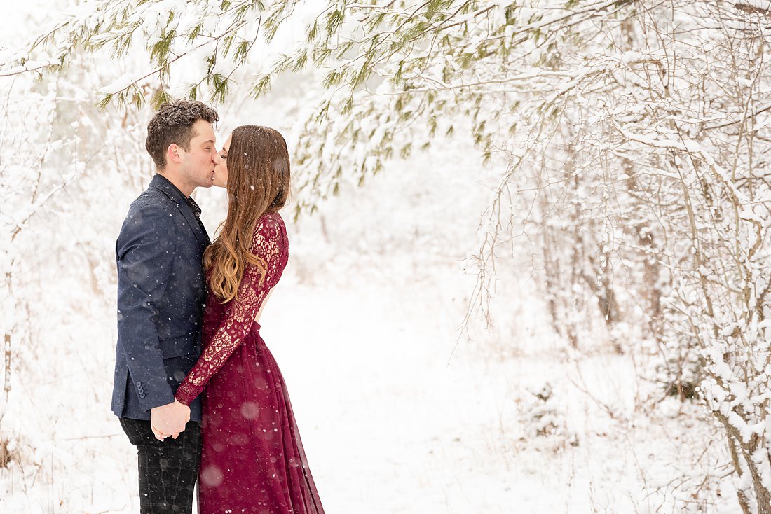 couple kissing under a tree at their winter engagement session